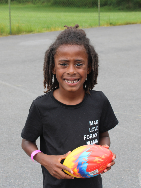 Young boy smiling with a rainbow football at Camp Cann-Edi-On