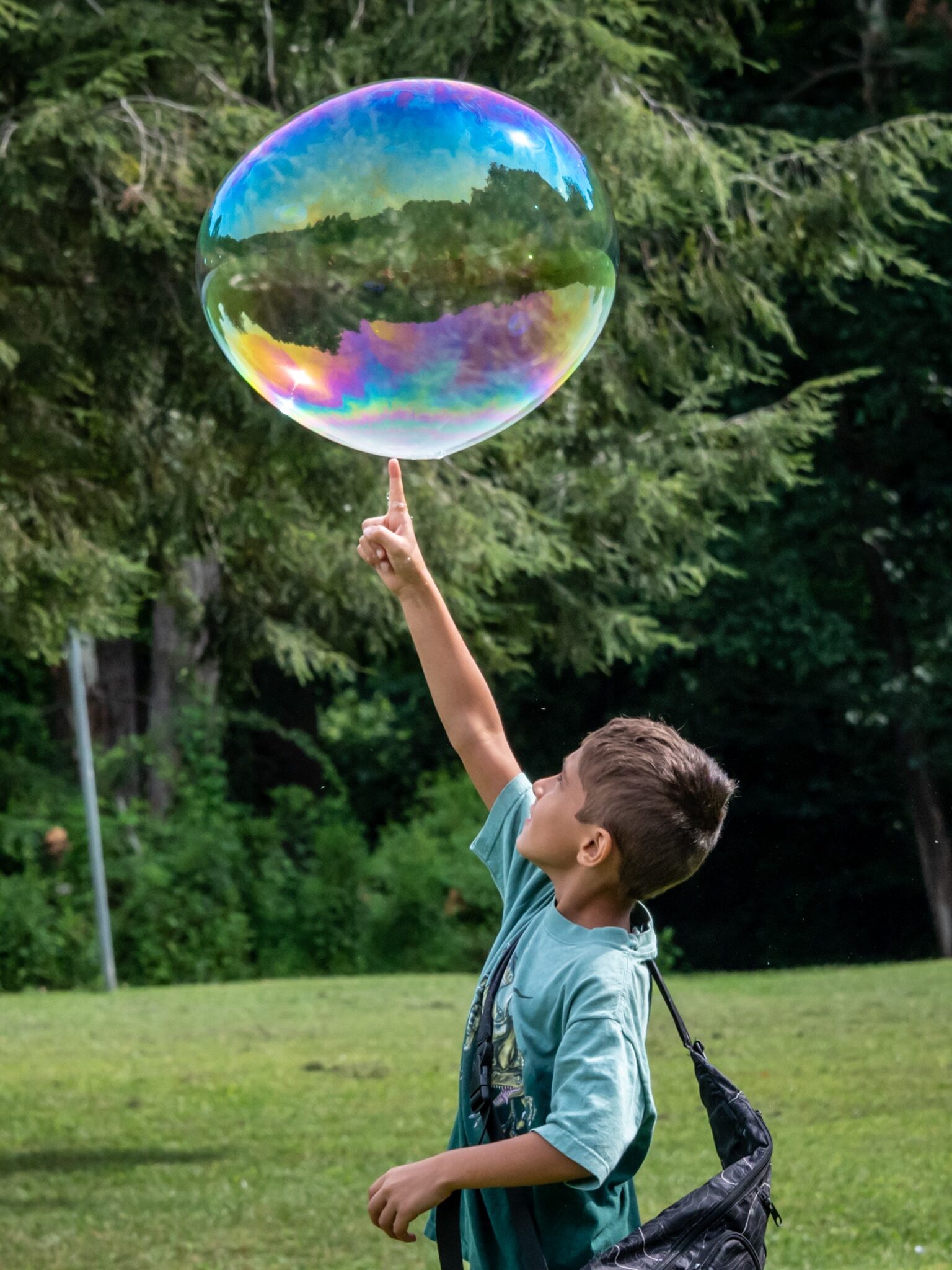 Young boy with a backpack popping a giant bubble