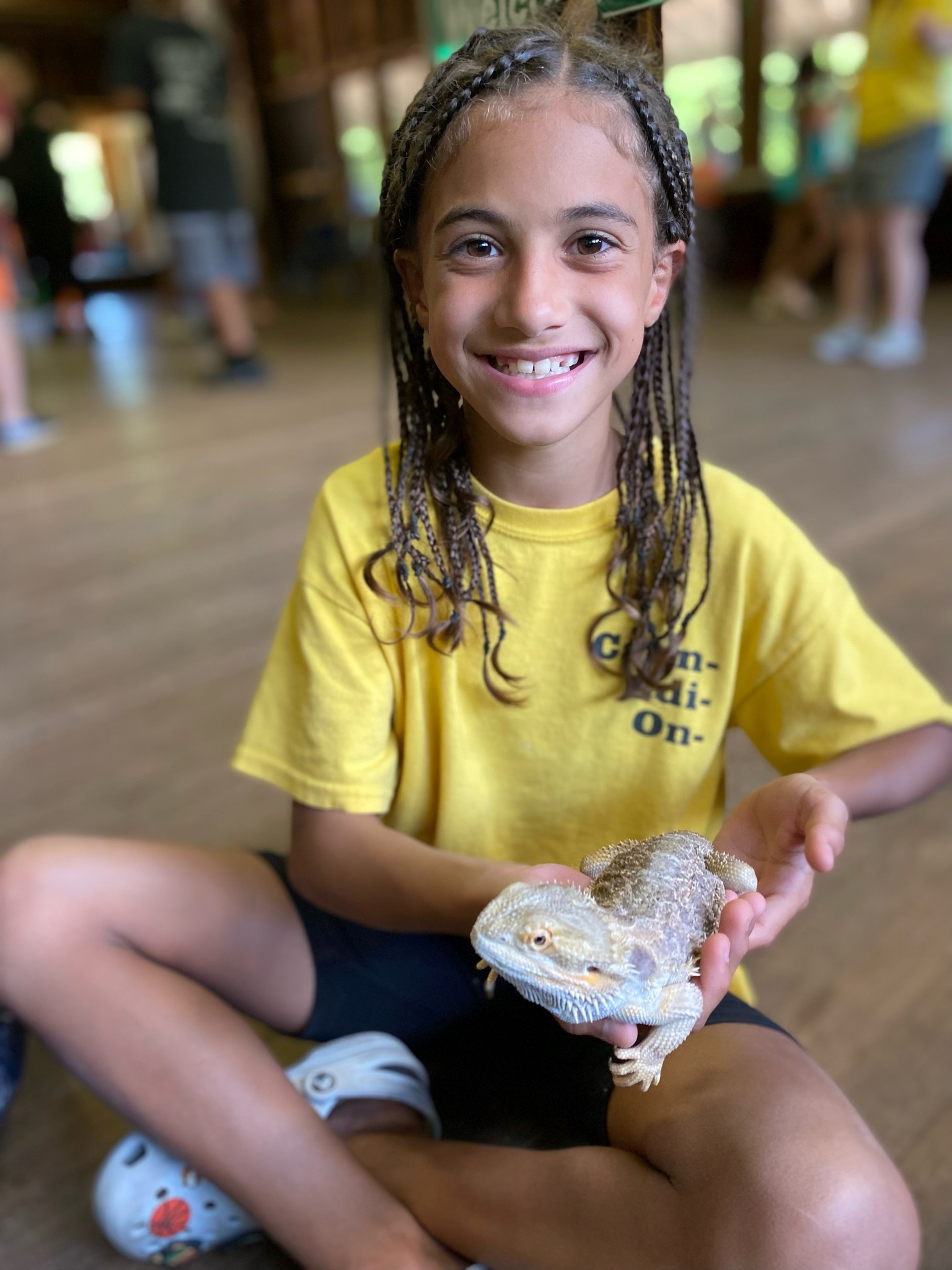 Young girl smiling while holding a bearded dragon at Camp Cann-Edi-On