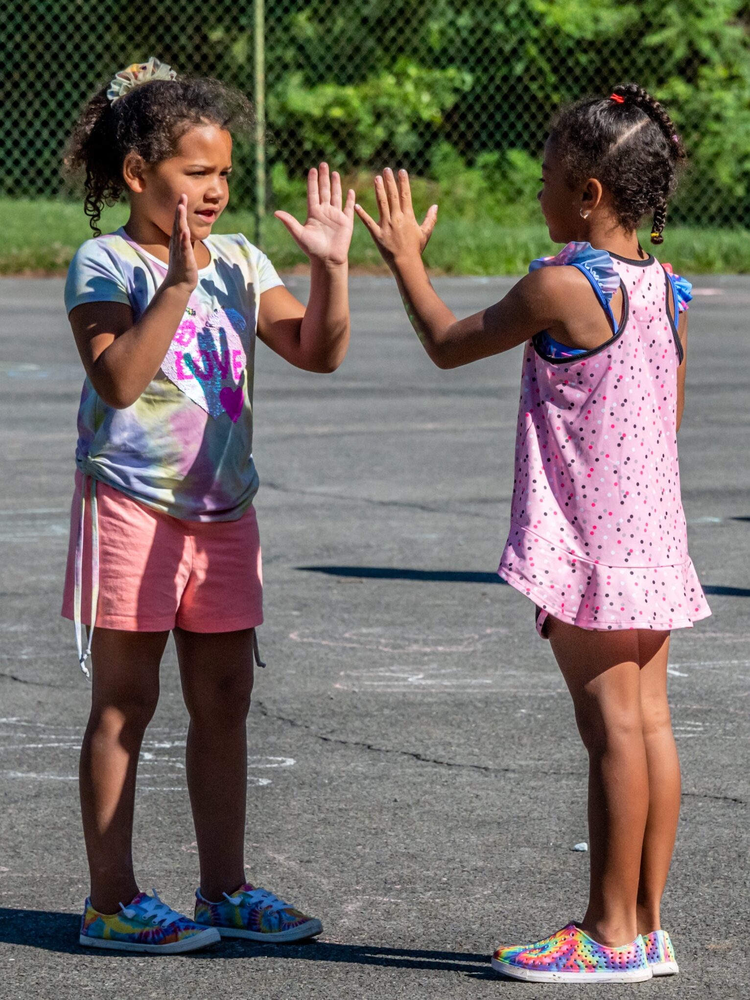 Two young girls playing a hand clapping game on the basketball court at Camp Cann-Edi-On