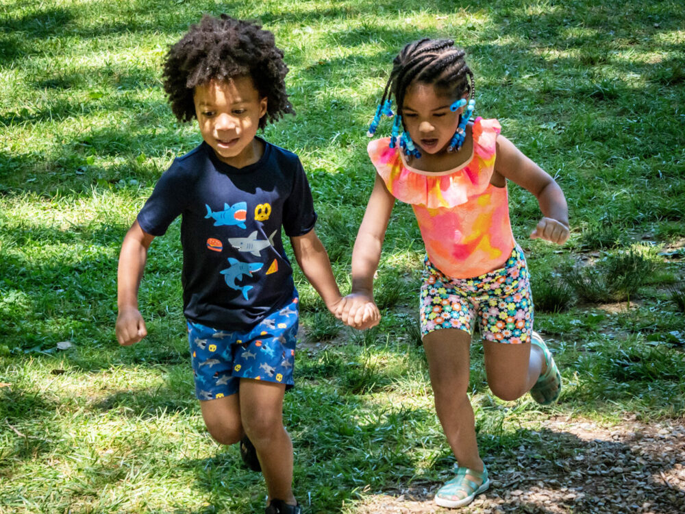 Two children holding hands and running in YWCA York's camp program