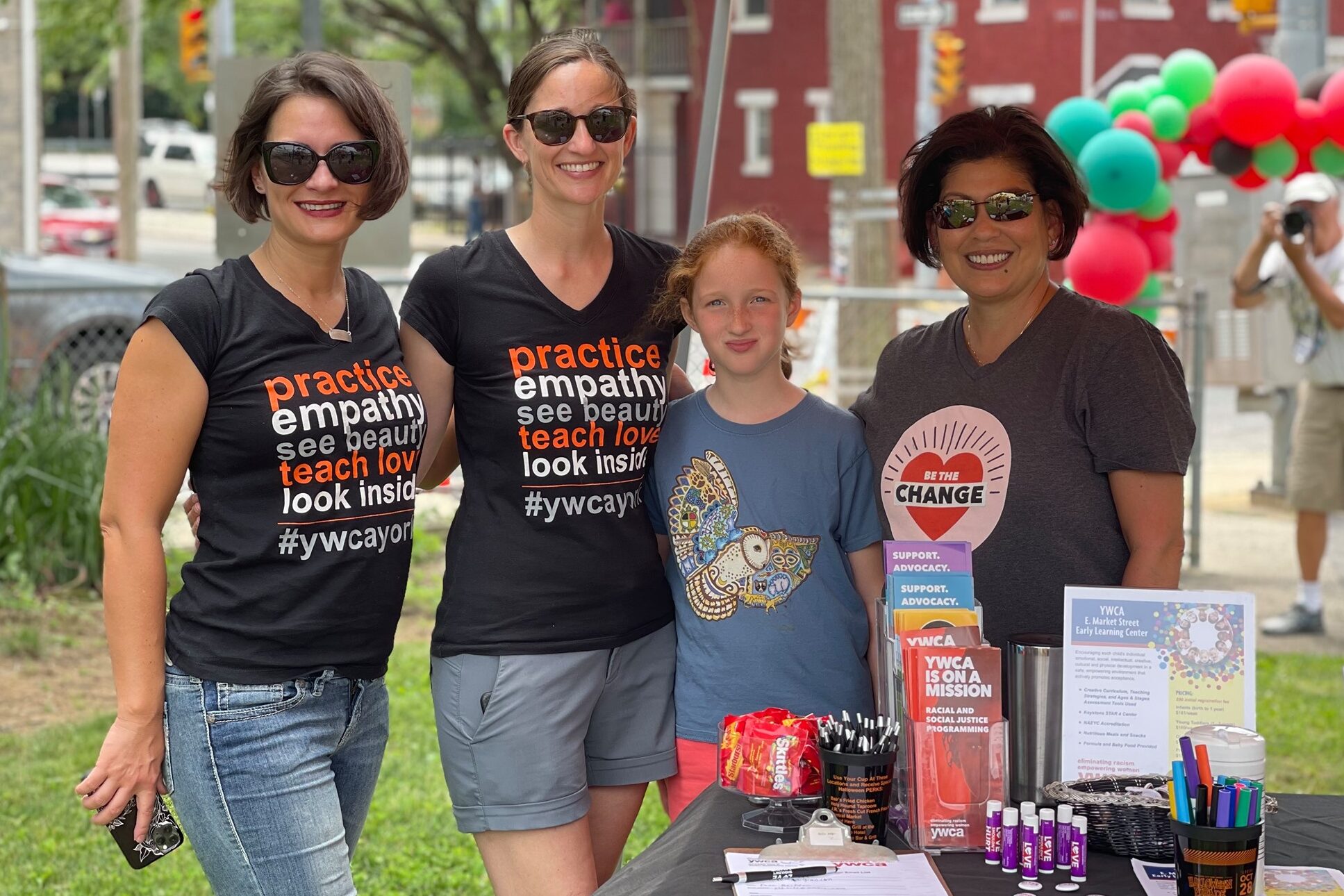 YWCA York Racial Justice Committee and staff members smiling at a community event with their table of resources and swag