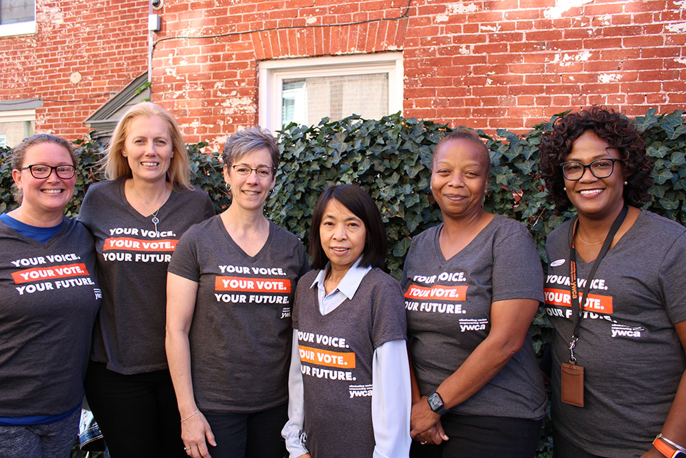 YWCA York staff posing together outside of the YWCA York building with their "Your Voice, Your Vote, Your Future" t-shirts