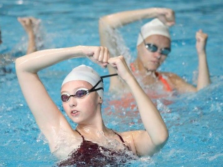York Synchro swimmers posing mid-routine with their heads and hands above water